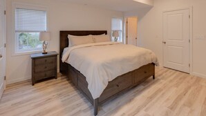 Une chambre à coucher avec un lit en bois, une table de chevet, une commode et une porte.