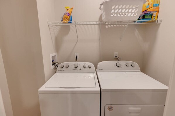 A laundry area with two white front-loading washing machines and a shelf above them holding cleaning supplies. - Luxury Ski Condo- Forest Ridge (Lincoln)