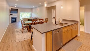 A modern kitchen with a central island, wooden cabinets, and a stainless steel dishwasher. - Luxury Ski Condo- Forest Ridge (Lincoln)