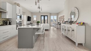 Une cuisine moderne dotée d’un îlot central, d’appareils électroménagers en acier inoxydable et d’un grand miroir.