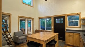 A spacious kitchen with a wooden table, bar stools, and a ceiling fan.