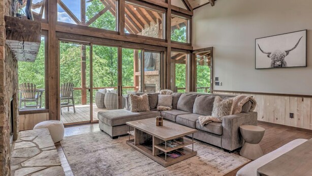 A spacious living room with a large sectional sofa, a coffee table, and a stone fireplace.