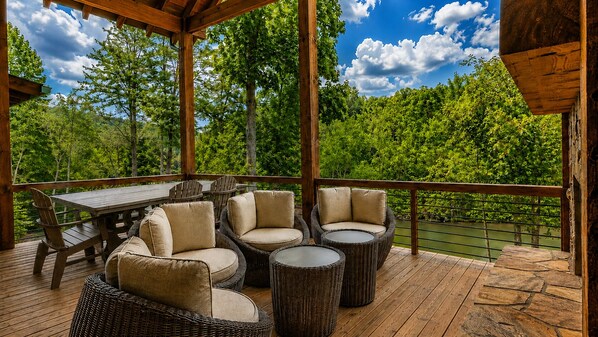 Une terrasse extérieure avec une table et des chaises en bois, entourée de verdure et offrant une vue sur les arbres.