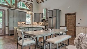 A spacious kitchen with a large island, grey cabinets, and a stone backsplash.