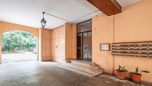 Una entrada con puerta de madera, una escalera y un buzón en la pared.