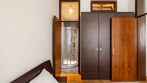 Un dormitorio con cama, armario, ducha y una ventana pequeña.