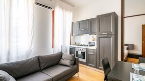Una cocina moderna con armarios grises, una mesa de comedor y un sofá.