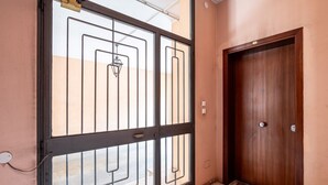 Una puerta de madera cerrada con una reja metálica, un enchufe y un felpudo con diseño en la entrada.