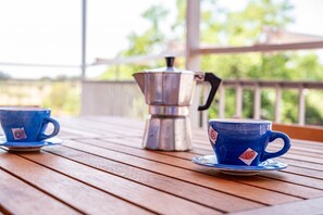 A wooden table with two blue cups and a silver coffee pot.