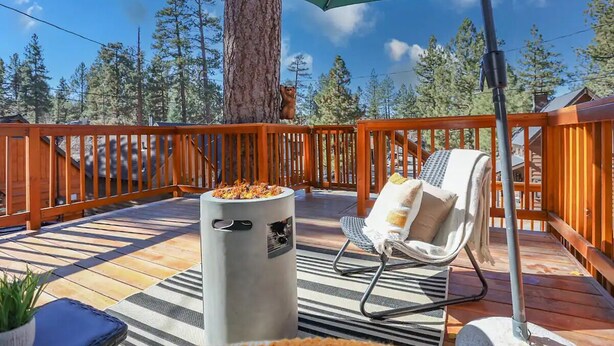 A wooden deck with a fire pit, a lounge chair, and a large umbrella. - Cozy Modern Cabin Near Lake, Spa, Village, & Ski Slope (Big Bear Lake)