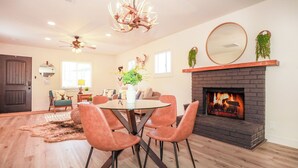 A modern living room with a fireplace, a dining area with orange chairs, and a large mirror on the wall. - Cozy Modern Cabin Near Lake, Spa, Village, & Ski Slope (Big Bear Lake)