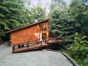 A log cabin with a wooden deck and a small porch.