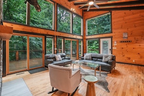 A spacious cabin with large windows, a wooden interior, and a cozy seating area.