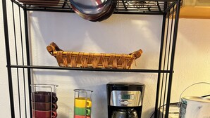Ein Küchenregal mit einer Kaffeemaschine, einem Becherhalter und einem Korb.