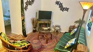 Ein Wohnzimmer mit Fernseher, Korbmöbeln, einem grünen Sofa und Wanddekoration.