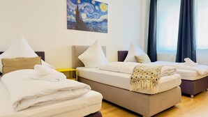 Ein Hotelzimmer mit zwei Betten, einem Bild an der Wand und Blick auf die Stadt durch das Fenster.