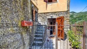 Ein Steinhaus mit einem Metallzaun, einer Holztür und einem roten Briefkasten.