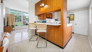 Eine moderne Küche mit Holzschränken, einer integrierten Kücheninsel und einem Essbereich mit zwei Stühlen.