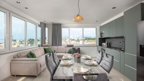 A modern living space with a dining area, kitchen, and large windows offering a city view. - Amazing apartment in Podstrana with WiFi (Podstrana)