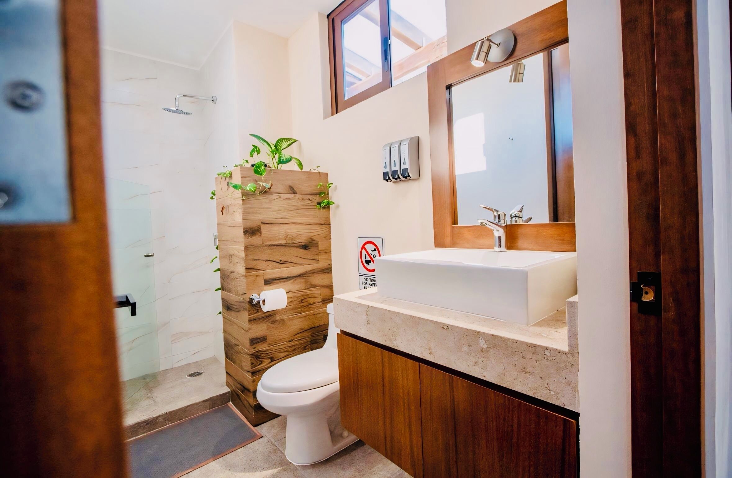 Ein modernes Badezimmer mit einer Wand in Holzoptik, einer weißen Toilette, einem Waschbecken mit Spiegel und einer Duschkabine.