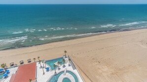 Vista aérea de un resort en la playa con piscina, palmeras y una playa de arena.