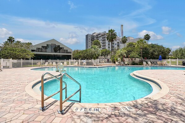 A swimming pool with a 3 ft 6 in. depth marker, surrounded by a white fence and lounge chairs.