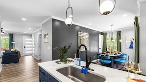 Una cocina moderna con una isla grande, pileta de acero inoxidable e iluminación colgante.