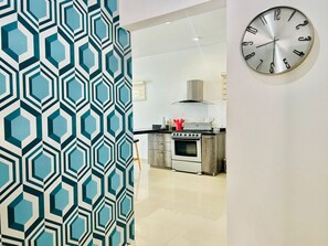 A modern kitchen with a stainless steel stove, a range hood, and a red pot on the counter. - Elegante depa super céntrico en zona dorada 1 (Mazatlán)