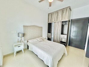 Quarto com cama, mesa de cabeceira e guarda-roupa.