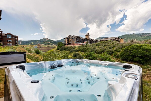 A hot tub with a view of a large building and surrounding landscape.