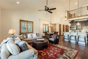 A spacious living room with a sofa, ottoman, and a dining area with chairs and a table.