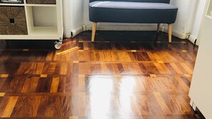 A room with a wooden parquet floor featuring a geometric star design, a blue sofa, and a white shelving unit with baskets. - Apartment Battistero XX Marzo (Parma)