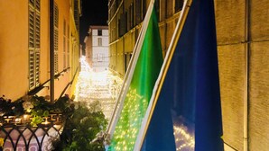 A narrow street with buildings on either side, a flag, and a decorative light display. - Apartment Battistero XX Marzo (Parma)