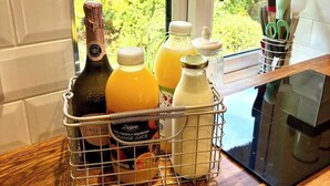 Una encimera de cocina con una botella de vino, zumo de naranja y leche.