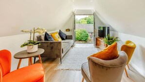 Un loft moderno con sofá, sillones, una mesita con una planta y televisor.