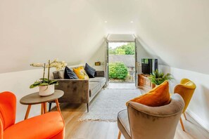 Un appartement moderne de style « loft » comprenant un canapé, des fauteuils, une petite table avec une plante et un téléviseur.