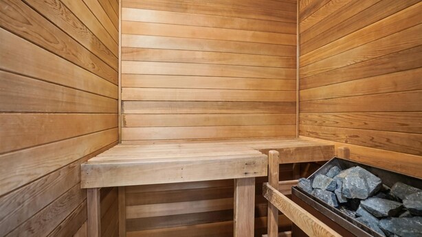 Een houten sauna met een bank en een bak met stenen.