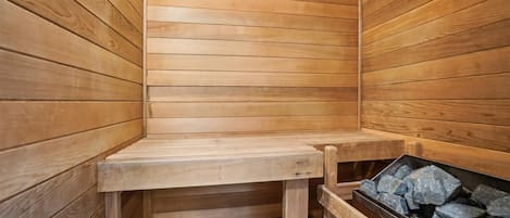 Un sauna en bois, avec un banc et un récipient rempli de pierres.