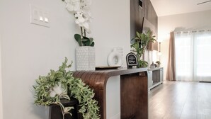 A modern reception desk with a wooden finish, a potted plant, and a sign that reads "MAKE YOURSELF HOME."