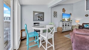 Una sala de estar moderna con comedor, televisor y una zona de estar acogedora.