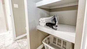 Een wasruimte met planken, een mand en een deur naar een andere kamer.