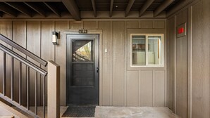 A black door with a sign above it, a window with a view, and a staircase leading up. - Fun Ski Condo - On Ski Bus Line - Pool & Hot Tub (Steamboat Springs)