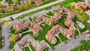 An aerial view of a residential area with multiple apartment buildings, a parking lot, and a swimming pool. - Fun Ski Condo - On Ski Bus Line - Pool & Hot Tub (Steamboat Springs)