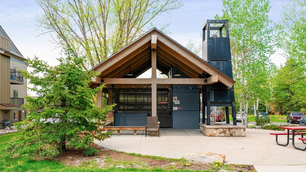 A covered pavilion with a sloped roof, benches, and a picnic table in a park setting. - Fun Ski Condo - On Ski Bus Line - Pool & Hot Tub (Steamboat Springs)