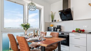 A modern kitchen with a dining area, large windows, and a view of the water. - Pet friendly apartment in Olpenitz (Olpenitz)