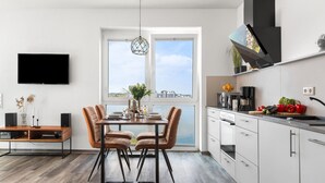 A modern kitchen with a large window, a dining area with a table and chairs, and a flat-screen TV mounted on the wall. - Pet friendly apartment in Olpenitz (Olpenitz)
