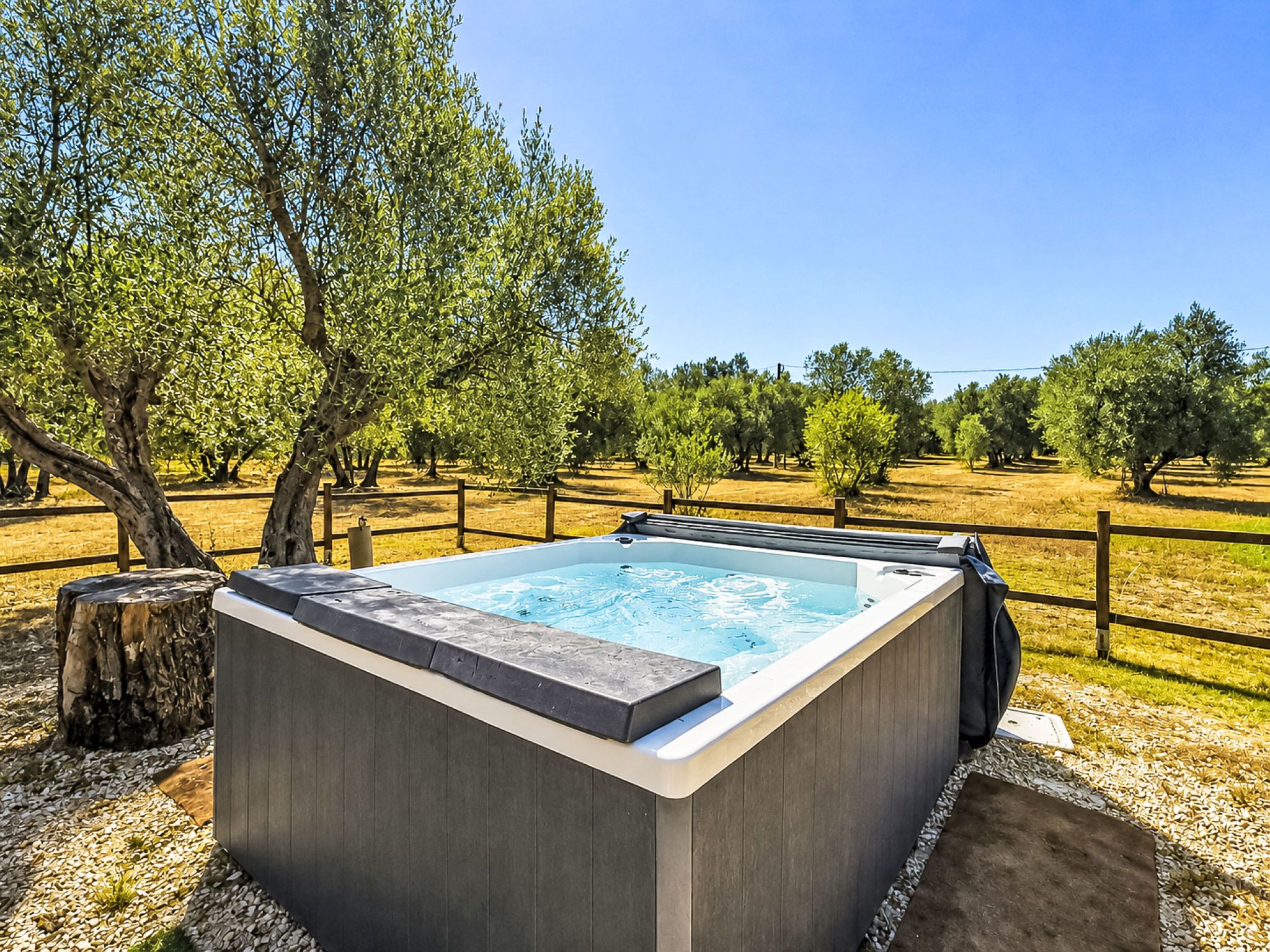 A hot tub in a natural setting with trees and a clear sky.