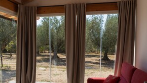A living room with a red sofa, a coffee table, and a view of an outdoor area with trees and a dirt path. - Grotta Porcina by Interhome (Lago di Vico)