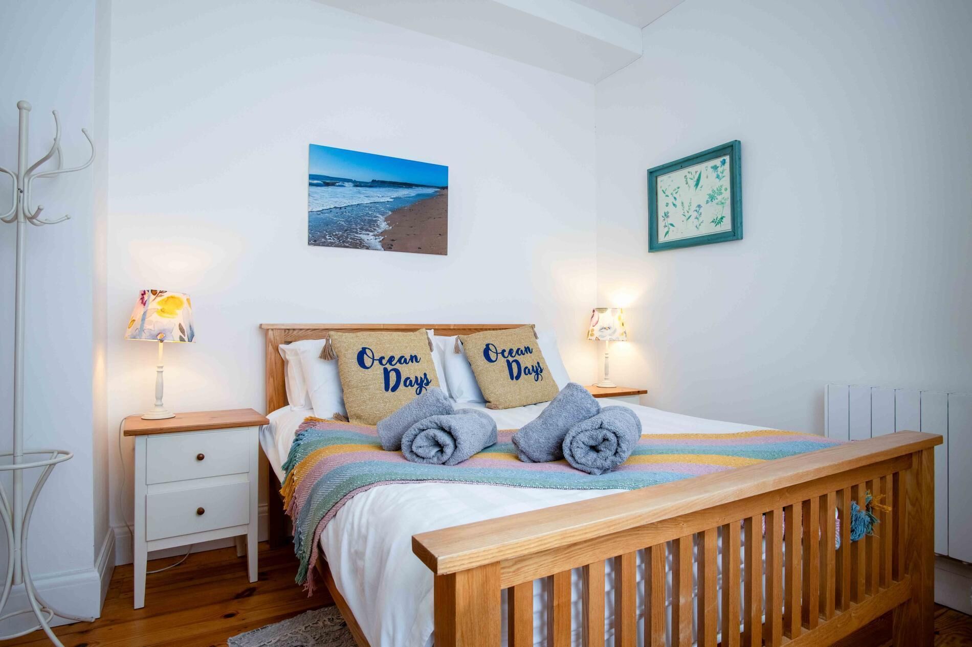 Une chambre à coucher avec un lit en bois, deux tables de chevet, une commode, une lampe et un tableau encadré au mur.