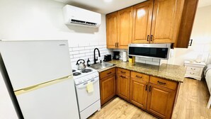 Una cocina con gabinetes de madera, un refrigerador blanco, una estufa, un microondas y un lavaplatos.